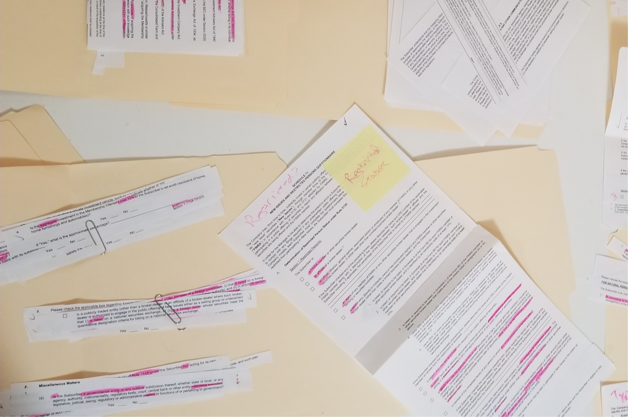 Physical affinity diagramming session with highlighted and cut-out contract questions spread across a table, grouped by topic with paper clips and sticky notes.